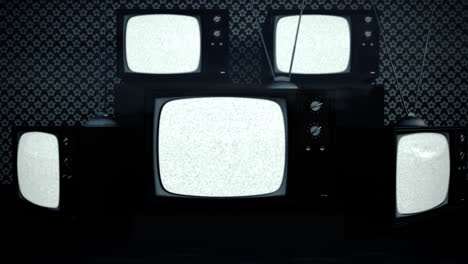 An-exhibition-of-old-fashioned-retro-color-tv-sets-with-antennas.-Electronic-devices-stack-in-front-of-vintage-wallpaper.-Obsolete-television-is-displaying-a-green-screen.