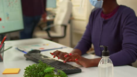 Close-up-of-black-woman-using-hand-sanitizer-in-office