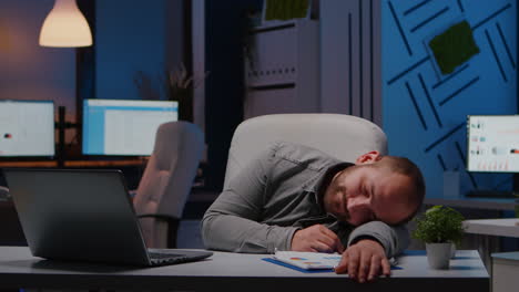 Exhausted-overworked-businessman-sleeping-on-desk-table-in-startup-business-office