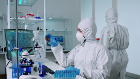 Scientist-in-ppe-suit-holding-petri-dish-while-studying-virus-samples