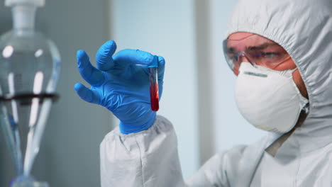 Scientist-holding-blood-sample-wearing-protection-suit