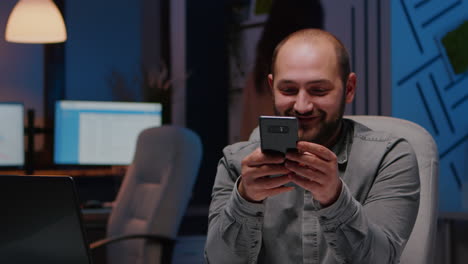 Entrepreneur-man-smiling-at-phone-while-writing-financial-strategy-planner