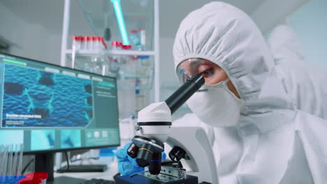 Nurse-in-ppe-suit-doing-medical-experiments-using-microscope