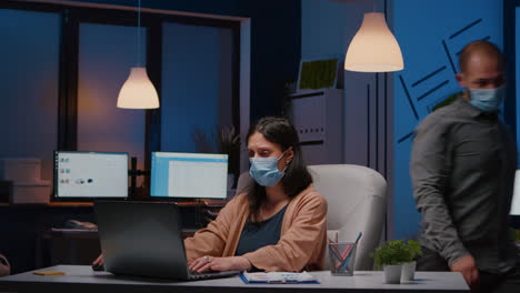 Overworked-entrepreneur-with-face-mask-against-covid19-working-in-startup-office
