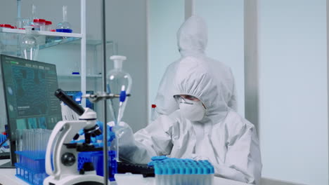 Ccientist-with-coverall-in-lab-performs-tests-with-blue-liquid