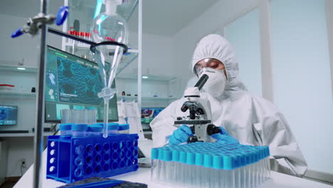 Scientist-in-protective-suit-conducting-virus-analysis-using-microscope