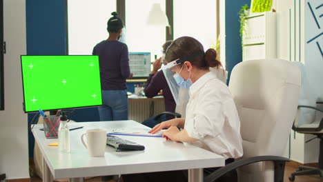 Manager-with-face-mask-typing-on-computer-with-green-screen