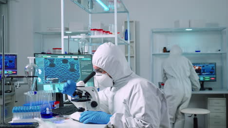 Scientist-in-ppe-suit-working-in-laboratory-using-modern-microscope