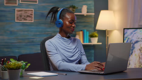 Smiling-black-designer-woman-with-headphones-listening-music