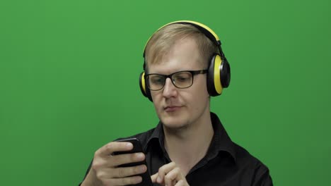 Guy-listens-to-music-in-wireless-yellow-headphones-and-dances.-Chroma-key