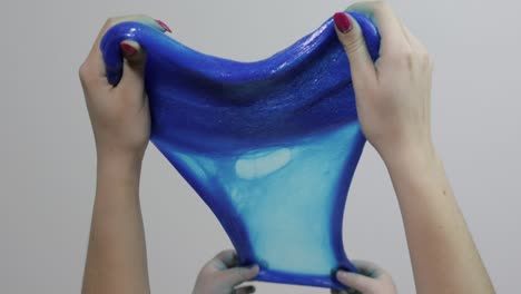 Woman-and-child-hands-playing-satisfying-blue-slime-gooey-substance.-Antistress