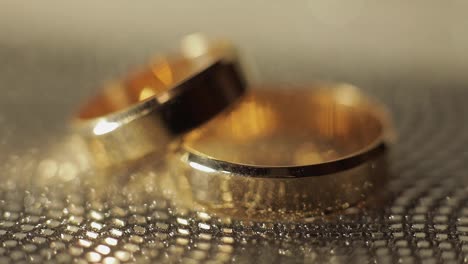 Wedding-gols-rings-lying-on-shiny-glossy-surface.-Shining-with-light.-Close-up