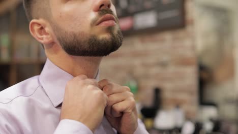 Groom-adjusts-the-shirt-in-barbershop-background.-Preparing-to-go-to-the-bride