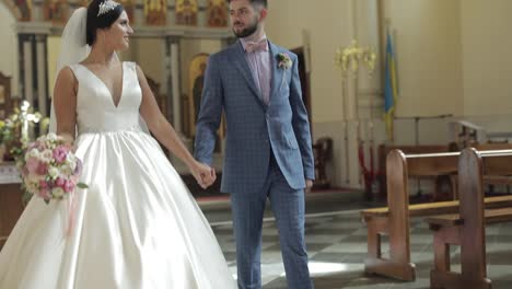 Elegant-bride-and-groom-walking-together-in-an-old-church.-Wedding-couple