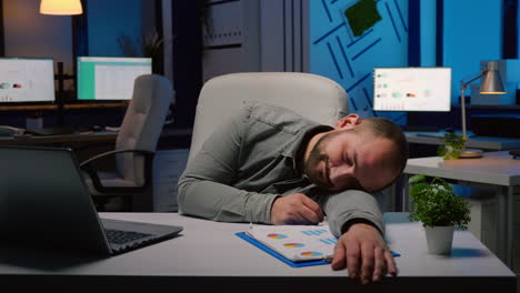 Exhausted-overworked-businessman-sleeping-on-desk-table-in-startup-business-office