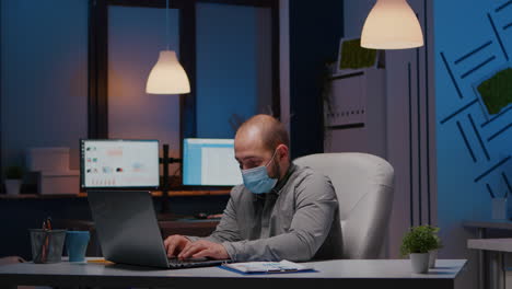 Overworked-businessman-with-face-mask-against-covid19-working-in-startup-office