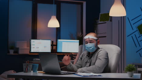 Workaholic-businessman-with-face-mask-and-visor-against-covid19-working-in-company-office