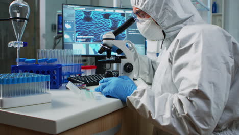 Scientist-in-protection-suit-looking-through-a-microscope
