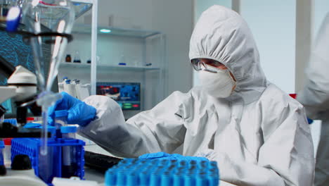 Researcher-in-coverall-testing-liquid-sample-using-test-tubes