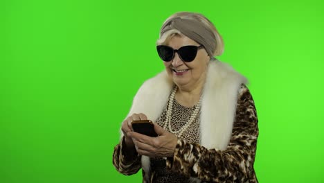 Caucasian-grandmother-woman-using-smartphone,-pointing-at-something-with-hand