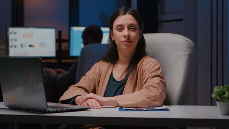Portrait-of-smiling-businesswoman-looking-into-camera-while-sitting-at-desk