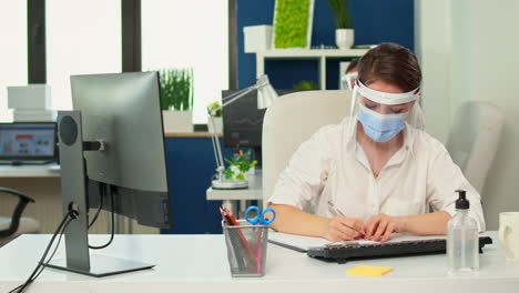 Businesswoman-with-mask-taking-notes-from-computer