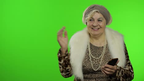 Kaukasische-Großmutter-Benutzt-Smartphone-Und-Zeigt-Mit-Der-Hand-Auf-Etwas