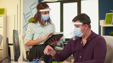 Employees-with-protection-masks-discussing-looking-at-computer