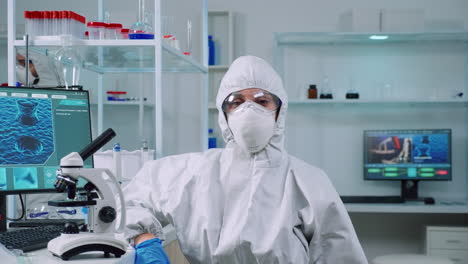 Tired-microbiologist-in-coverall-sitting-in-laboratory-looking-at-camera