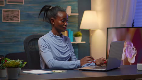 Black-woman-typing-on-computer-and-writing-on-stick-notes