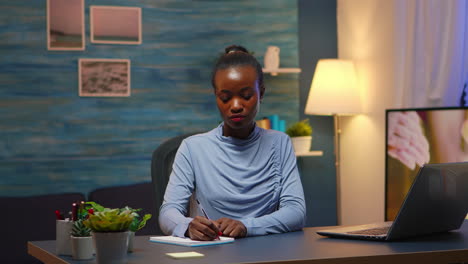 Mujer-De-Negocios-Negra-Escribiendo-En-Un-Cuaderno-Trabajando-Horas-Extras