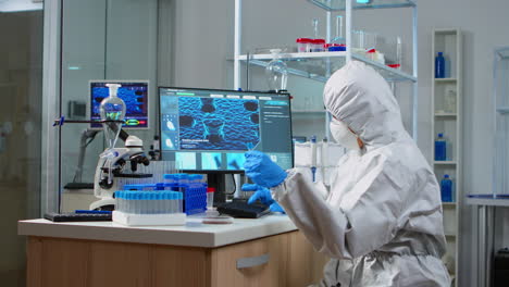 Chemist-with-coverall-looking-at-virus-test-in-equipped-lab