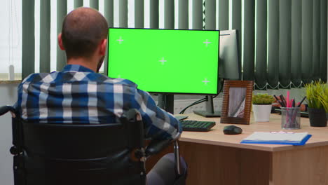 Disabled-freelancer-looking-at-pc-with-green-screen