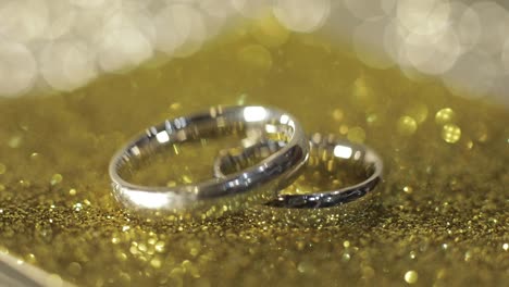 Wedding-silver-rings-lying-on-shiny-glossy-surface.-Shining-with-light.-Close-up