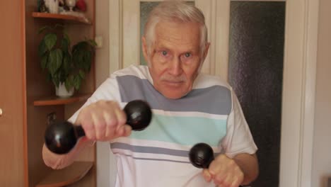 Senior-elderly-caucasian-man-doing-sports-exercises-with-dumbbells-at-home