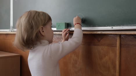 Mädchen-Zeichnet-Im-Klassenzimmer-Mit-Kreide-An-Die-Tafel.-Bildungsprozess
