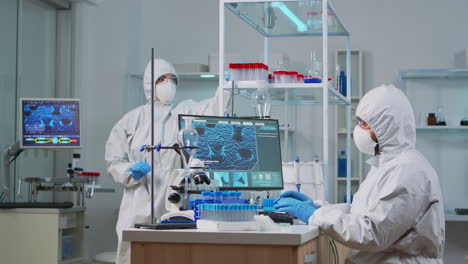 Chemist-in-ppe-suit-typing-on-computer-checking-virus-development