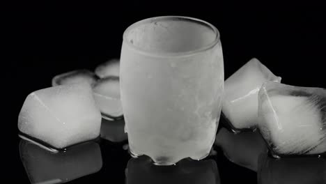 Pour-vodka-into-icy-glass-with-ice-cubes-placed-on-a-black-background