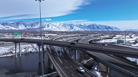 Drone-view-of-traffic-on-spaghetti-bowl-in-Salt-Lake-City,-snowy-mountains