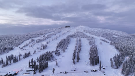 Aerial-view-away-from-the-slopes-of-Iso-Syote,-colorful-winter-sunset-in-Finland