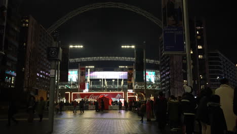 Menschen-Stehen-Mit-Ihren-Kindern-Schlange,-Um-Nachts-Den-Coca-Cola-Weihnachtstruck-Vor-Dem-Wembley-Stadion-Unter-Dem-Berühmten-Torbogen-Des-Stadions-Zu-Besuchen