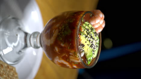 Vertical-close-up-of-a-seafood-shrimp-cocktail-served-in-a-glass-cup-with-avocado-and-some-shrimp-on-top