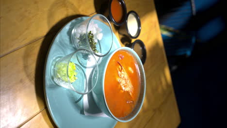 Vertical-slow-motion-of-a-seafood-soup-with-a-crab-in-it-served-on-a-blue-plate-at-a-traditional-mexican-restaurant