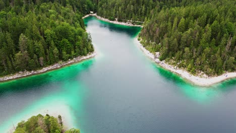 Scenic-aerial-of-forest-lake,-Lake-Eibsee-in-Bavarian-Alps,-Germany