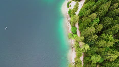 Overhead-view-of-Eibsee-lakeshore-in-the-Bavarian-Alps-with-green-tinted-water,-Stand-Up-Paddles-in-lake-water,-Germany