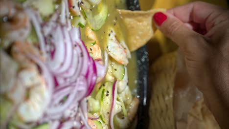 Close-up-of-a-female-hand-catching-a-shrimp-using-a-tortilla-ship-in-a-traditional-mexican-plate-called-aguachile