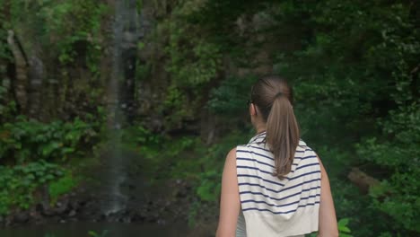 model-girl-looking-at-a-waterfall-in-the-jungle-in-Madeira-Portugall-,-deep-in-the-green-forest