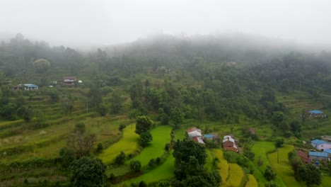 Aerial-flyover-tropical-lush-landscape-of-Nepal-with-foggy-sky-and-village-on-top