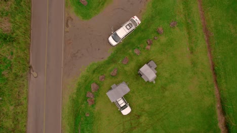 Drop-down-view-of-2-white-set-up-campervan-vehicle-in-field-close-to-road