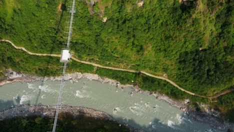 Aerial-birds-eye-shot-of-tropical-landscape-with-river-,-path-and-suspension-bridge-with-Bungee-Jumping